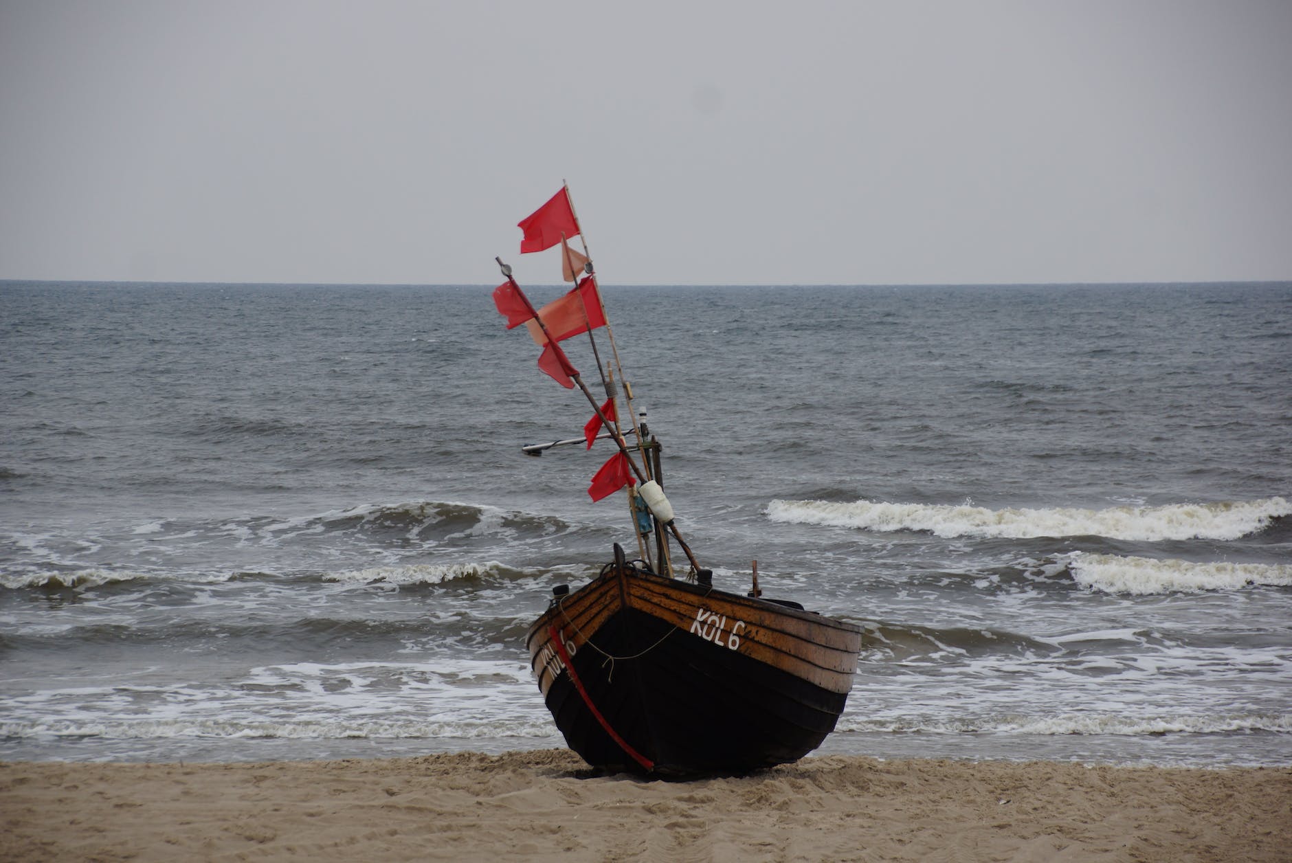 brown boat with red flags on the seashore
