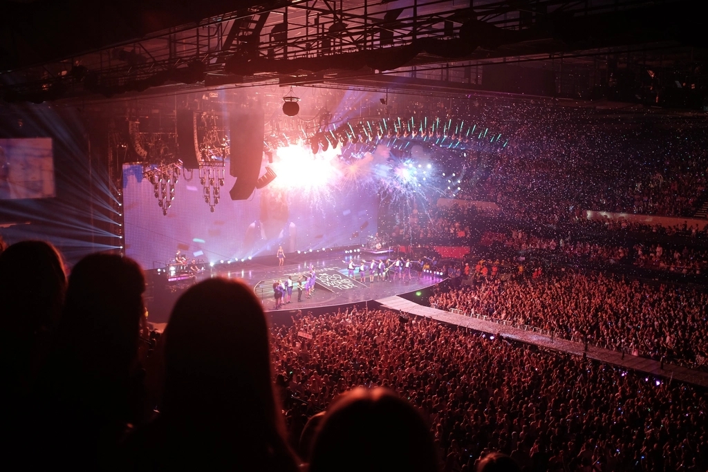 photo of a stage and concert full of thousands of people and bright lights with Taylor Swift on the stage.